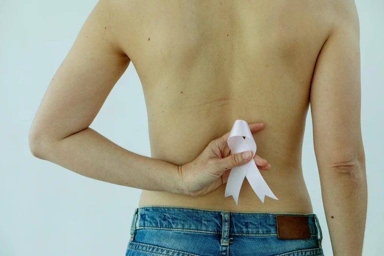 a woman with a pink ribbon on her back, inspired by Ren Hang, pexels contest winner, antipodeans, medical labels, paper cutout, ad image, marked muscles