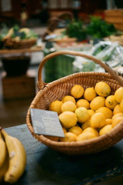 a basket of lemons and bananas on a table, by Julian Hatton, pexels, at the counter, 2 5 6 x 2 5 6 pixels, fantastic vendor interior, cream