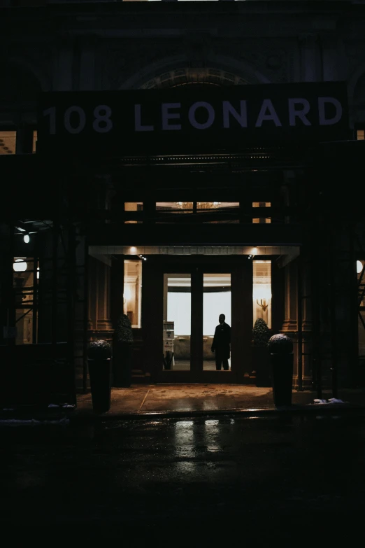 a person standing in front of a building at night, an album cover, by Leonard Bahr, unsplash contest winner, doorway, “leonardo dicaprio, headlights turned on, leaving a room