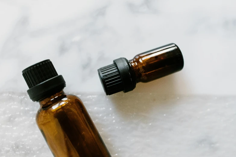 a bottle of essential oil on a marble surface, by Carey Morris, trending on pexels, brown, sustainable materials, close - up on face, homemade