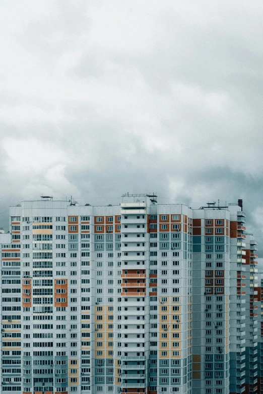 a group of tall buildings sitting next to each other, by Adam Marczyński, pexels contest winner, modernism, soviet suburbs, stormclouds, flat - color, overcast gray skies