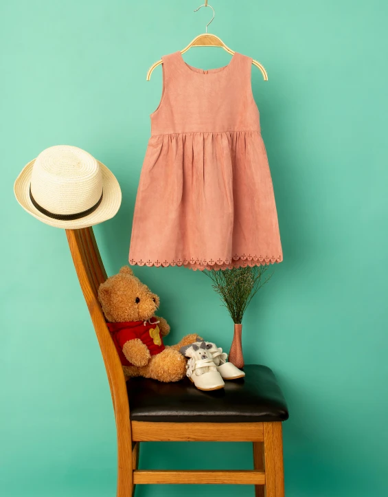 a teddy bear sitting on a chair next to a dress and hat, an album cover, inspired by Elsa Beskow, pexels contest winner, fullbody view, terracotta, toddler, high resolution product photo
