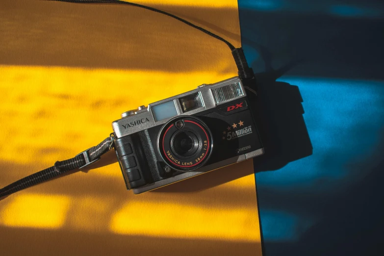 a close up of a camera on a table, a picture, coloured film photography, on a yellow canva, konica minolta, looking down on the camera