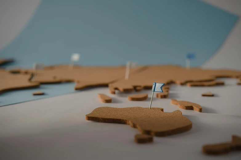 a map with a pin in the middle of it, a 3D render, trending on unsplash, conceptual art, sand banks, clay animation, made of cardboard, close up shot from the side