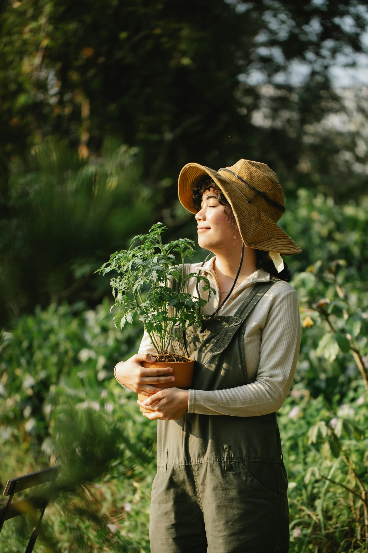 a woman in a hat holding a potted plant, inspired by Ruth Jên, pexels contest winner, renaissance, wearing farm clothes, gemma chan, thriving ecosystem, profile image