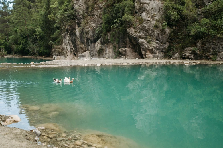 a group of people floating in a body of water, in between a gorge, teal landscape, sichuan, swimming