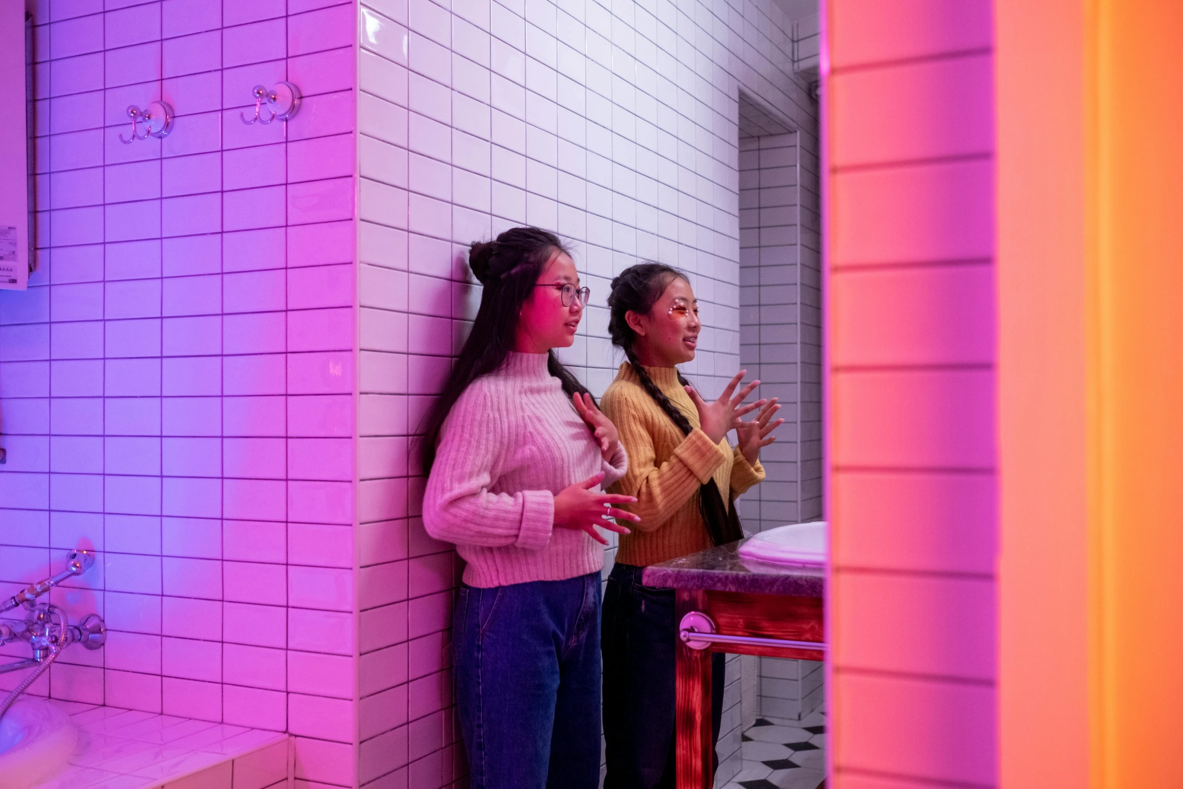 a couple of women standing next to each other in a bathroom, interactive art, brightly lit pink room, ruan jia and brom, tactile buttons and lights, with cinematic colour palette