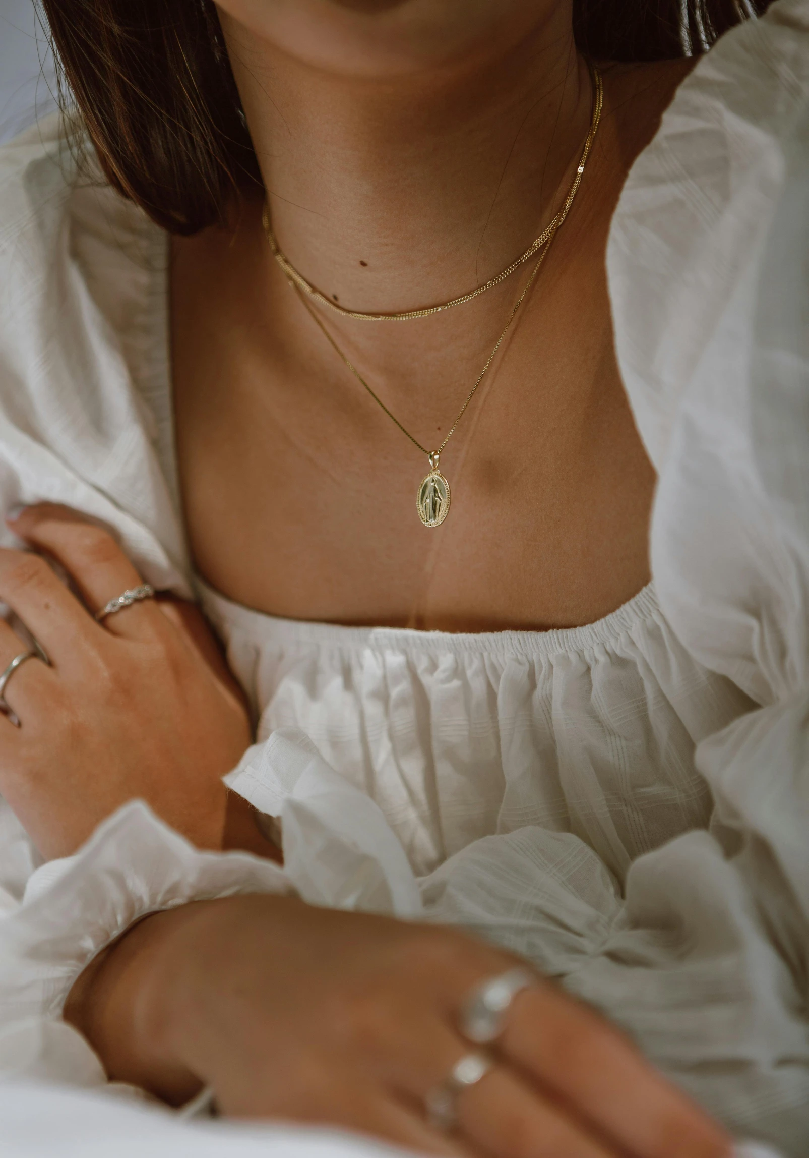 a close up of a person laying on a bed, inspired by Elsa Bleda, renaissance, small necklace, beautiful gold saint, wearing a light shirt, virgin mary