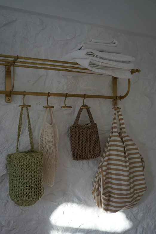 three bags hanging on a wall next to a towel rack, by Helen Stevenson, unsplash, renaissance, brass, olive green, cottagecore, cast