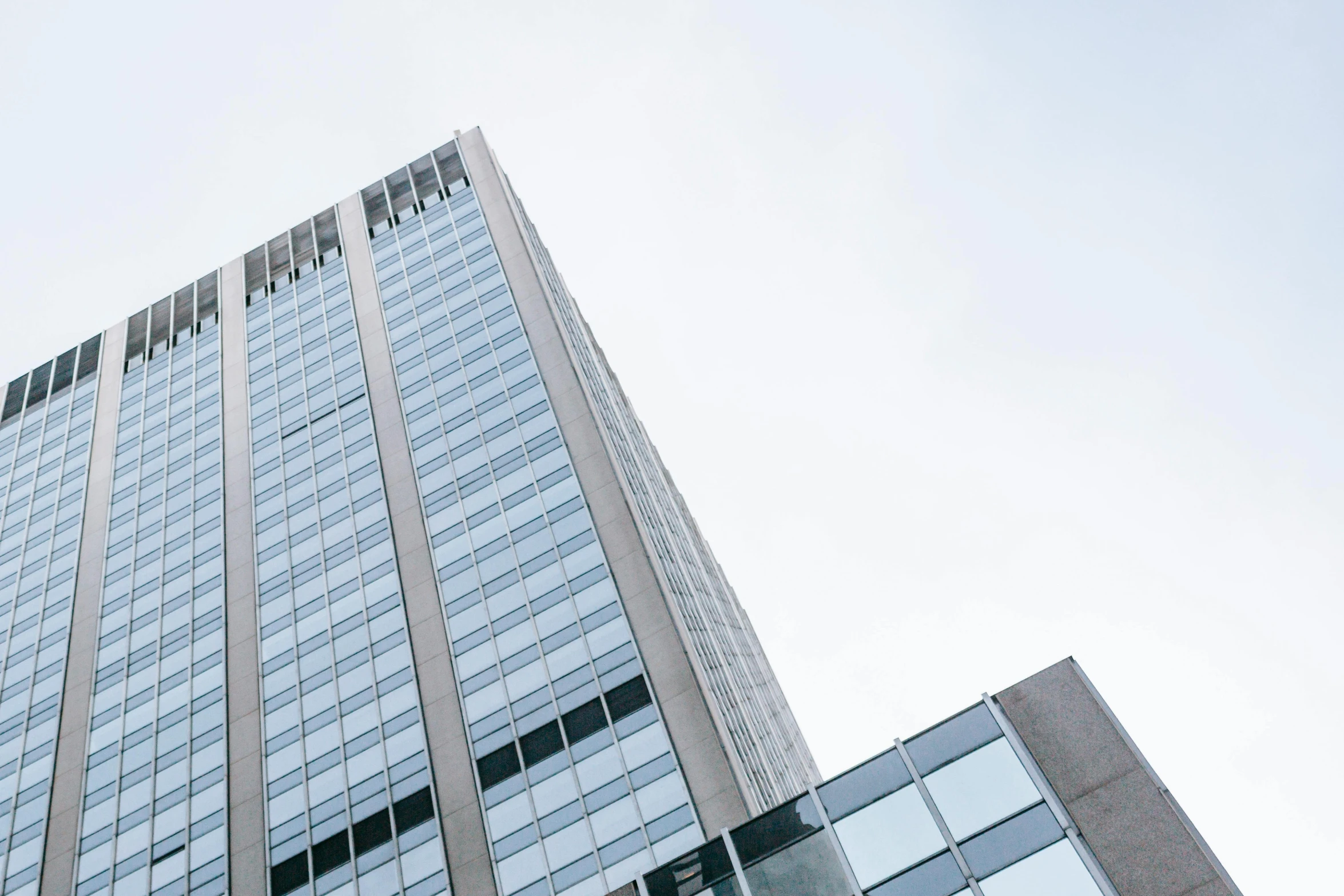 a tall building with a clock on top of it, a picture, unsplash, brutalism, clear sky above, full of clear glass facades, uhq, grey