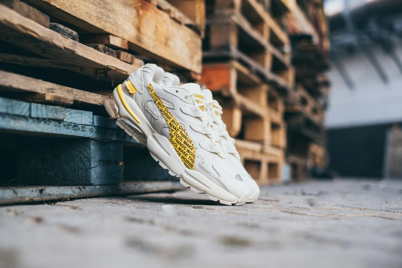 a pair of white sneakers sitting on top of a wooden pallet, graffiti, yellows, official store photo, nimbus, replicas