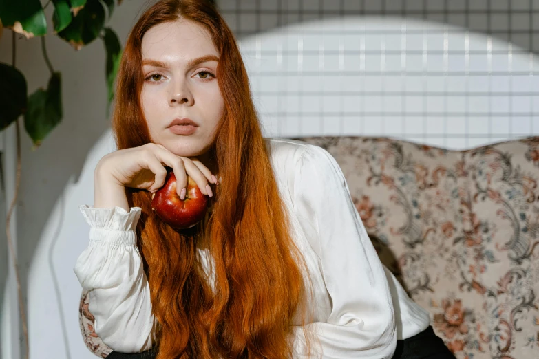 a woman sitting on a couch holding an apple, inspired by Elsa Bleda, trending on pexels, renaissance, long ginger hair, 15081959 21121991 01012000 4k, androgynous person, teenager girl