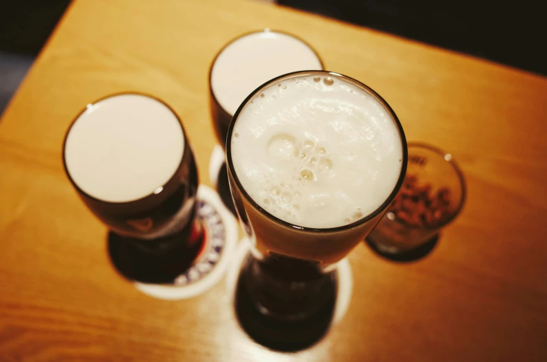 two glasses of beer sitting on top of a wooden table, unsplash, japanese akihabara cafe, 2 0 0 0's photo, 🎨🖌️, high angle close up shot