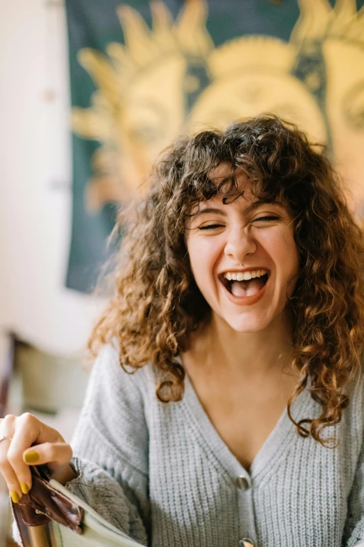 a woman sitting at a table with a plate of food, trending on pexels, happening, mutahar laughing, brown curly hair, portrait of teenage girl, giddy smirk