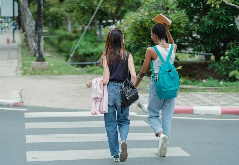 two women walking across a crosswalk holding hands, pexels contest winner, happening, college students, holding books, asian descent, sea - green and white clothes