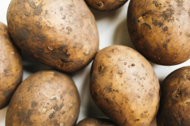 a pile of potatoes sitting on top of a white surface, by Carey Morris, unsplash, renaissance, portrait image, brown:-2, grey, closeup