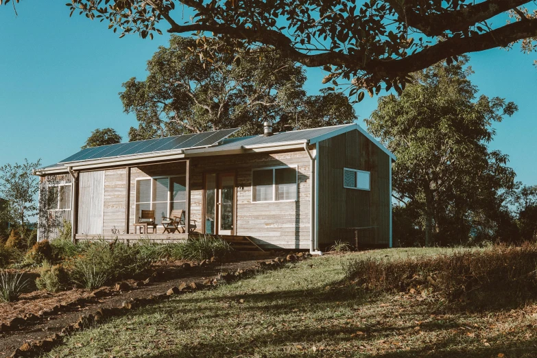 a small house sitting on top of a hill, a portrait, by Jessie Algie, unsplash, luxurious wooden cottage, bulli, profile image, sunlit