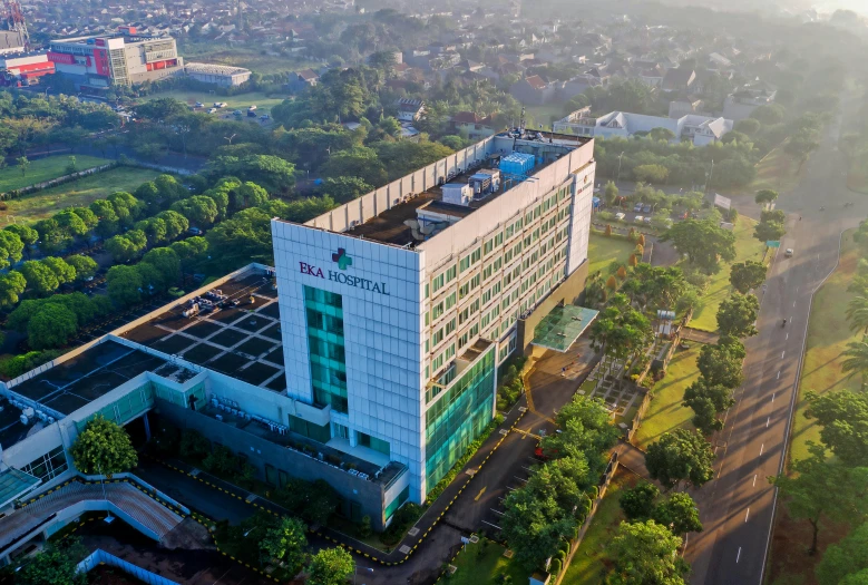 a large building sitting on top of a lush green field, a portrait, shutterstock, south jakarta, hospital in background, aerial view, square