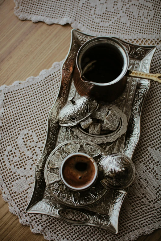 a silver tray topped with two cups of coffee, a still life, by Riad Beyrouti, trending on unsplash, hurufiyya, made of intricate metal and wood, turkish and russian, breakfast, brown