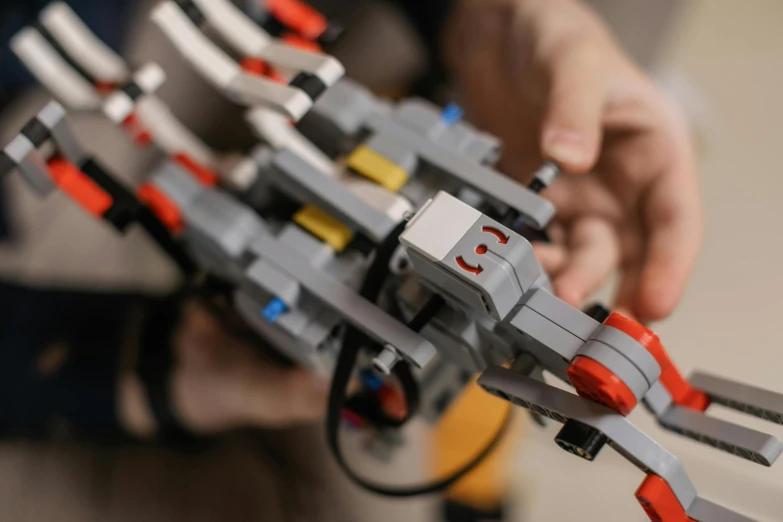 a close up of a person holding a lego gun, pexels contest winner, bauhaus, extended robotic arms, avatar image, mechanical engineering, close-up from above