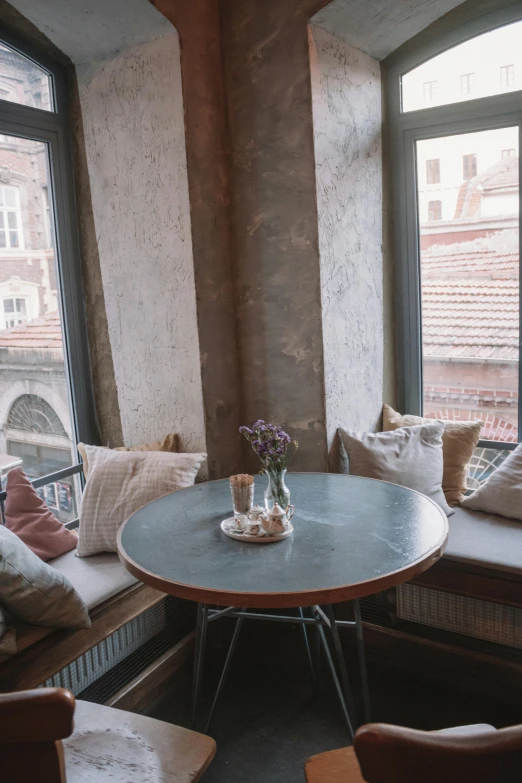 a couple of chairs and a table in a room, by Emma Andijewska, unsplash contest winner, bay window sofa, breakfast, budapest, muted pastel colors