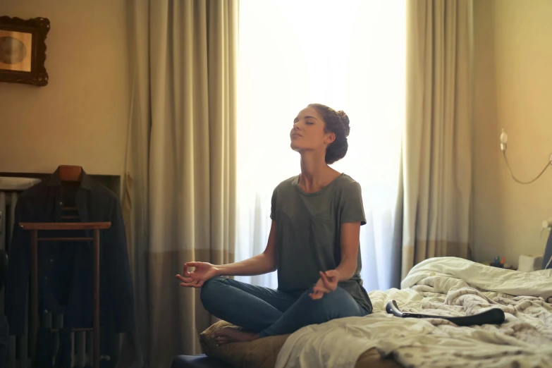 a woman sitting on top of a bed in a bedroom, pexels, meditating in lotus position, a person standing in front of a, profile image, hard breathing