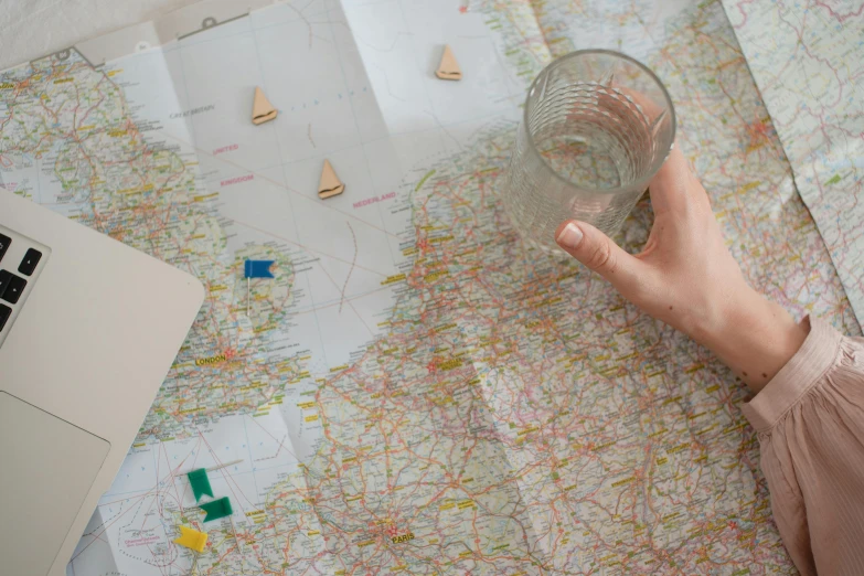 a person holding a glass on top of a map, inspired by Vija Celmins, scattered props, 'wherever you go, detail shot, sail