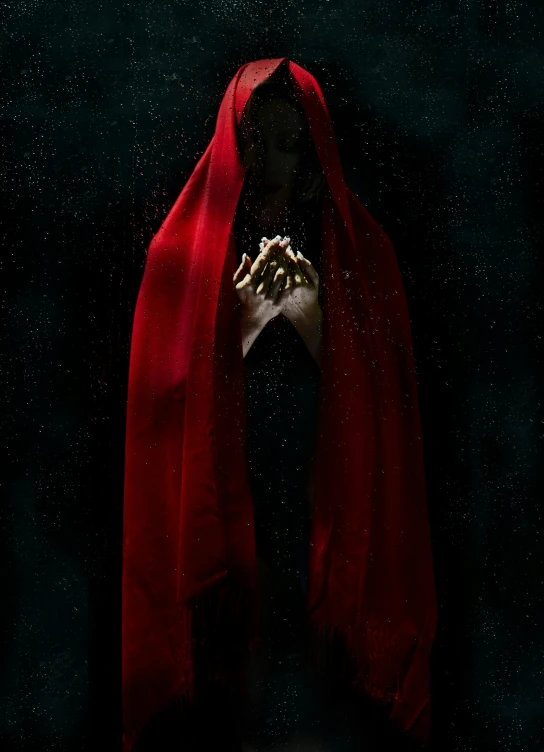 a woman in a red cloak standing in front of a black background, poster art, pexels contest winner, art photography, a seance, promo image, religious imagery