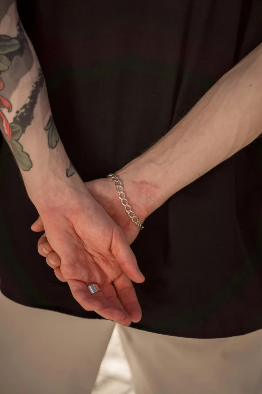 a close up of two people holding hands, a tattoo, inspired by Nan Goldin, non-binary, handcuffed, video still, ilustration