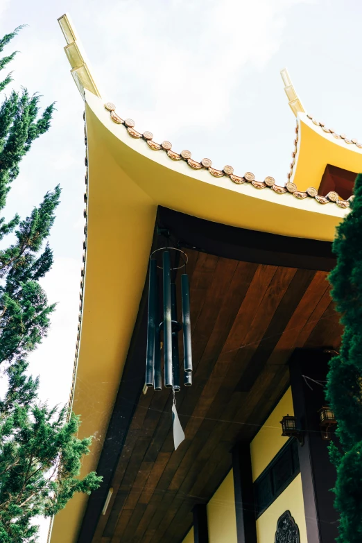 a yellow and black building with a tree in front of it, inspired by Gong Kai, unsplash, art nouveau, pagoda with a lot of wind chimes, close-up from above, high arched ceiling, square