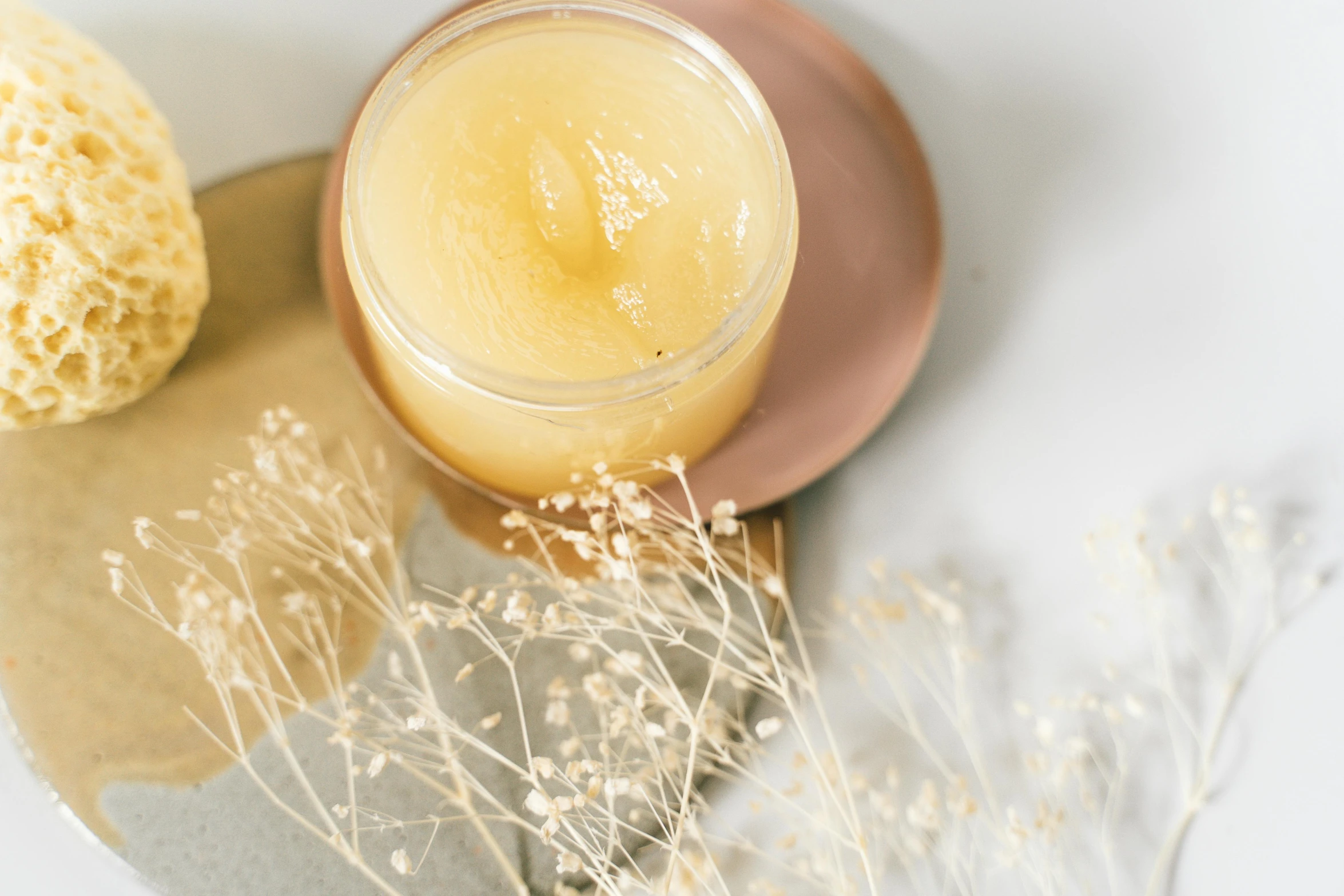 a jar of honey sitting on top of a plate, by Emma Andijewska, dewy skin, soft vibes, with lemon skin texture, sparkling