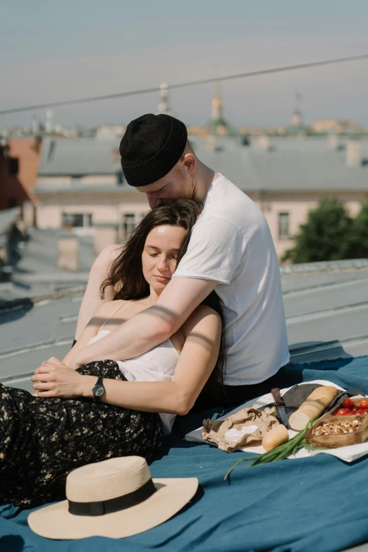 a man and woman sitting on a blanket on top of a roof, holding each other, angelina stroganova, snacks, embrace