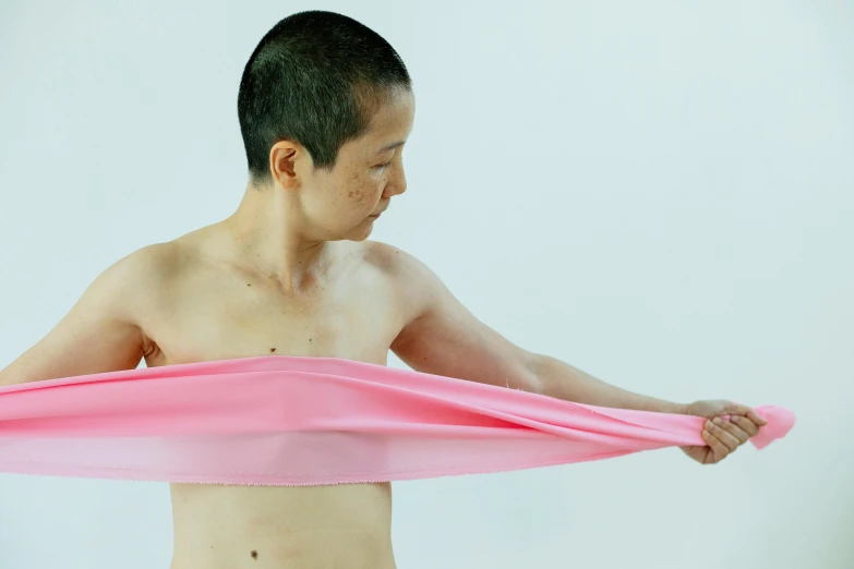 a man holding a pink cloth over his chest, inspired by Fei Danxu, unsplash, gutai group, nonbinary model, narumi kakinouchi, rubbery-looking body, looking left