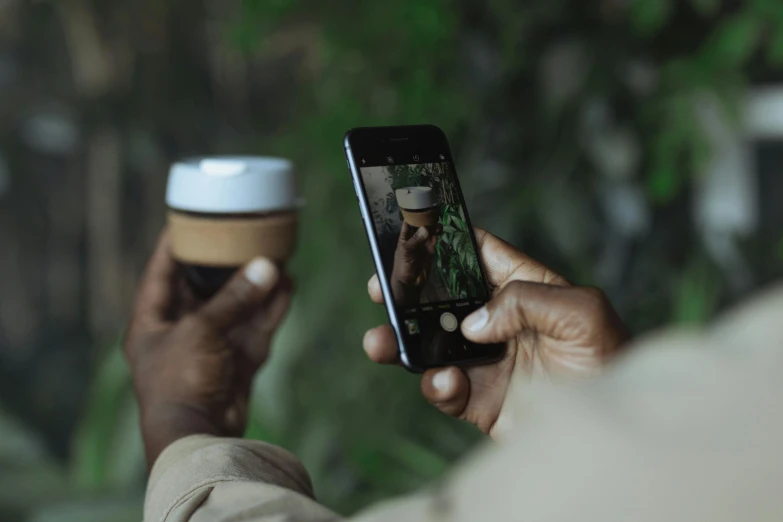 a man holding a cup of coffee and a cell phone, a picture, trending on unsplash, wildlife photo, man is with black skin, avatar image, instagram post