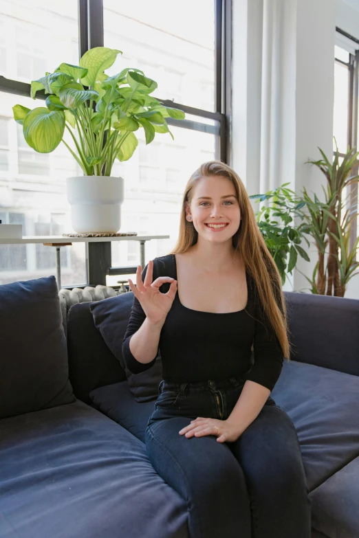 a woman sitting on a couch in a living room, a picture, giving a thumbs up to the camera, sydney sweeney, in new york city, profile image