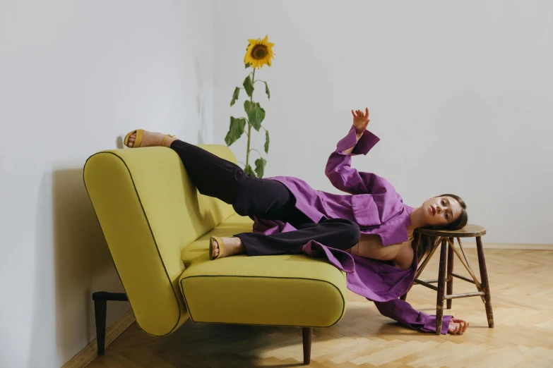 a woman laying on top of a yellow couch, inspired by Orazio Gentileschi, trending on pexels, baroque, wearing a purple detailed coat, full body sarcastic pose, cropped shirt with jacket, julia hetta