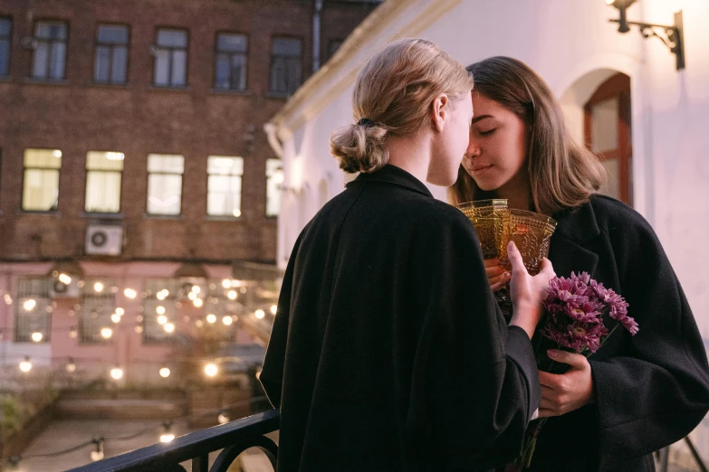 a couple of women standing next to each other on a balcony, pexels contest winner, neo-romanticism, lesbian kiss, candlelit, swedish, flowers around