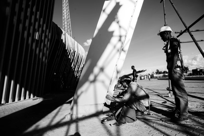 a black and white photo of a construction worker, unsplash, temporary art, in the sun, parametric structure, vendors, kneeling