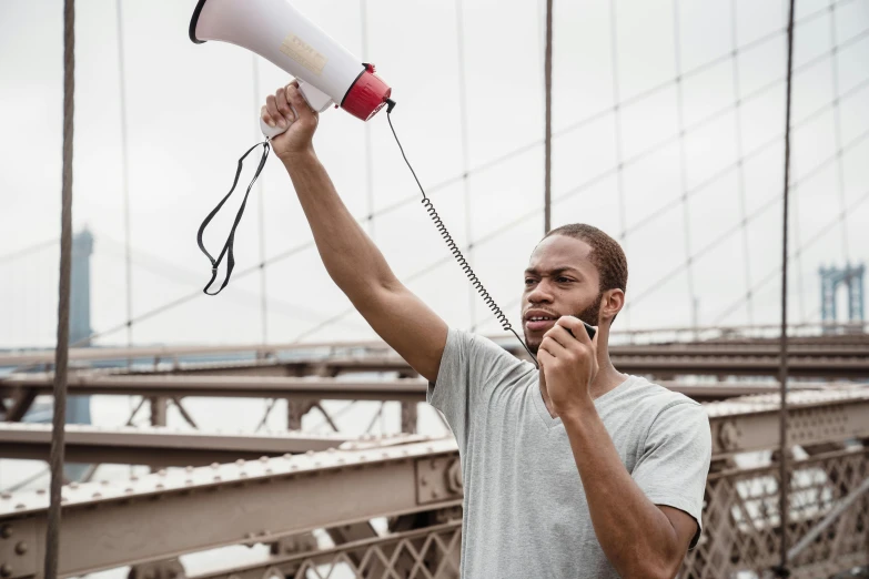 a man talking on a cell phone while holding a megaphone, by Niko Henrichon, pexels contest winner, athletic muscle tone, pewdiepie selfie at a bridge, protest movement, 15081959 21121991 01012000 4k