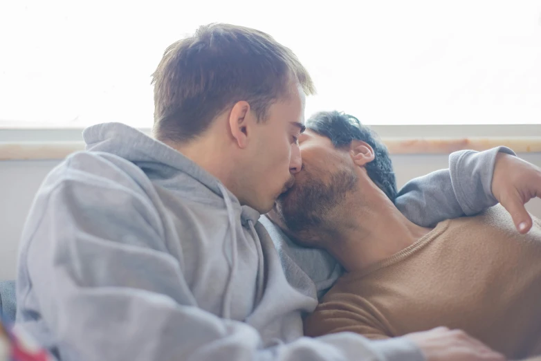 a man laying on top of a bed next to a woman, a photo, pexels, lesbian kiss, two buddies sitting in a room, bowater charlie and brom gerald, looking outside