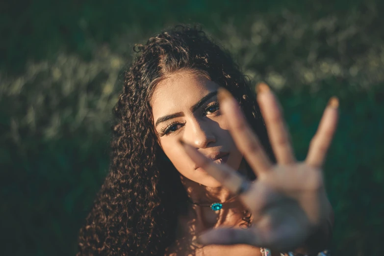 a woman making a stop sign with her hands, a picture, trending on pexels, hurufiyya, brown curly hair, hamsa hand, avatar image, selfie photo