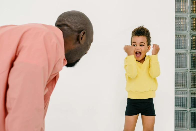 a man standing next to a little girl on a scale, pexels contest winner, shouting, yellow clothes, black man, facing away