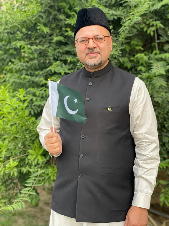 a man in a black vest holding a pakistan flag, an album cover, pexels contest winner, headshot profile picture, low quality photo, official government photo, wearing traditional garb