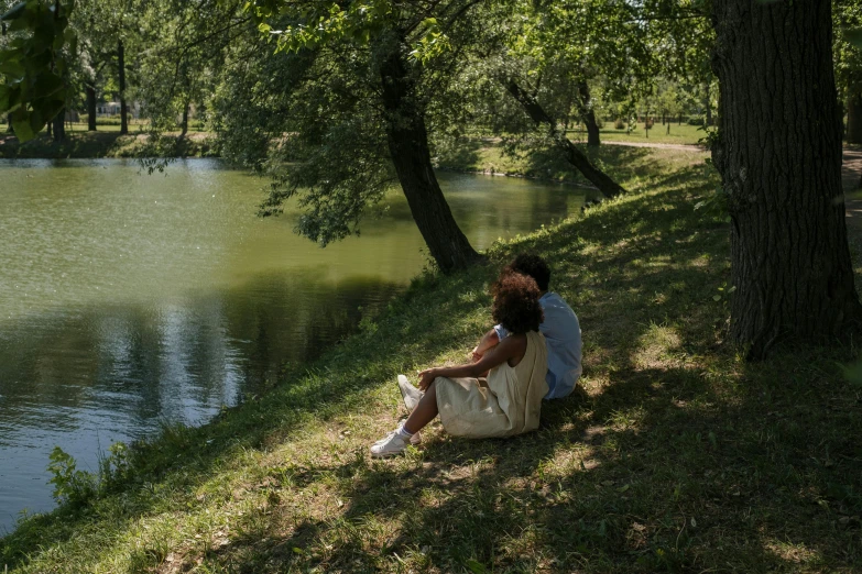 a woman sitting on the bank of a river, by Mirko Rački, romantic couple, under the soft shadow of a tree, cinematic lut, small lake