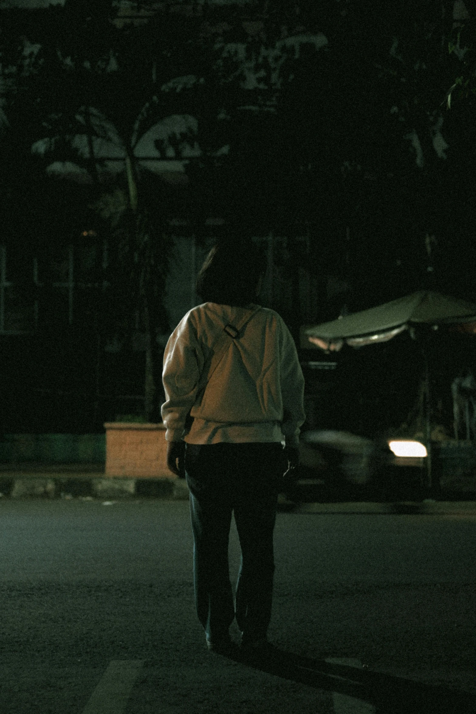 a man walking down a street at night, jakarta, standing with her back to us, movie frame still, **cinematic