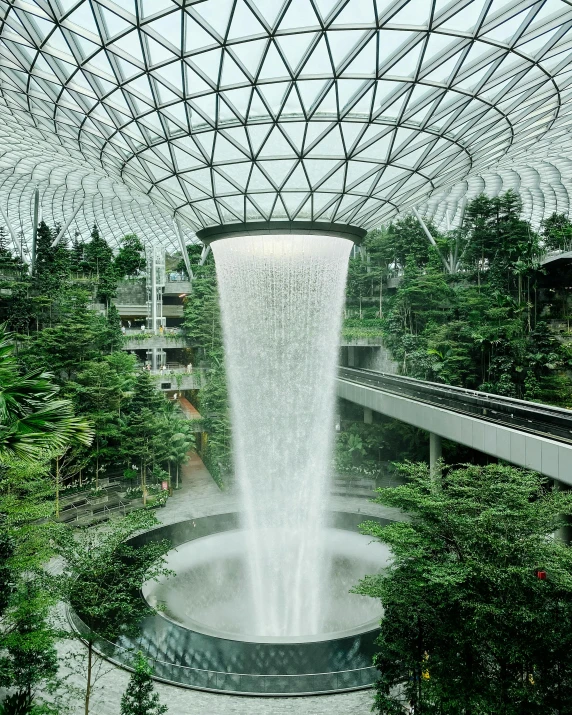 the inside of a building with a waterfall coming out of it, inspired by Cheng Jiasui, unsplash contest winner, singapore esplanade, lush garden spaceship, airport, roofed forest