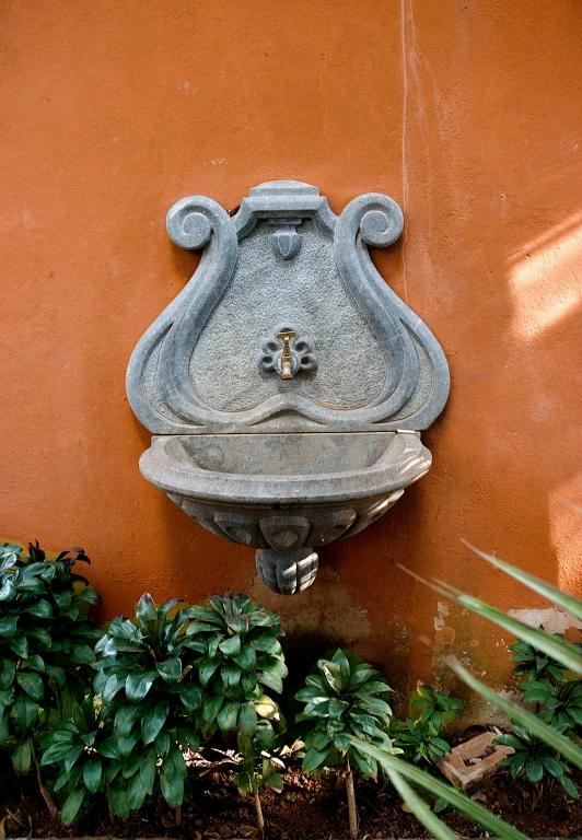 a water fountain sitting on the side of a building, sienna, keyhole, square