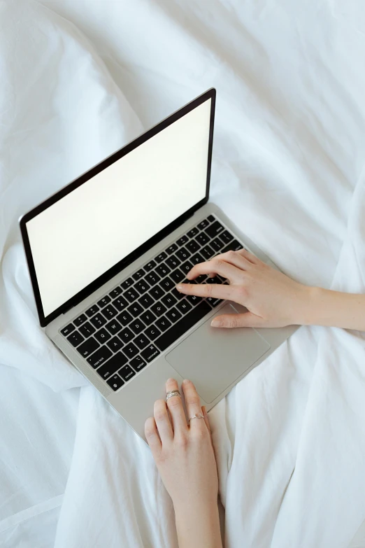 a woman laying in bed using a laptop computer, pexels, sleek hands, on a pale background, high angle, 6 : 3 0 am