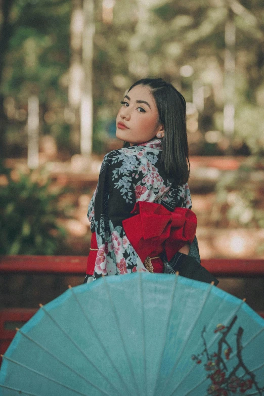 a woman sitting on a bench holding a blue umbrella, inspired by Itō Shinsui, pexels contest winner, portrait of mulan, shawl, cindy avelino, fashion pose