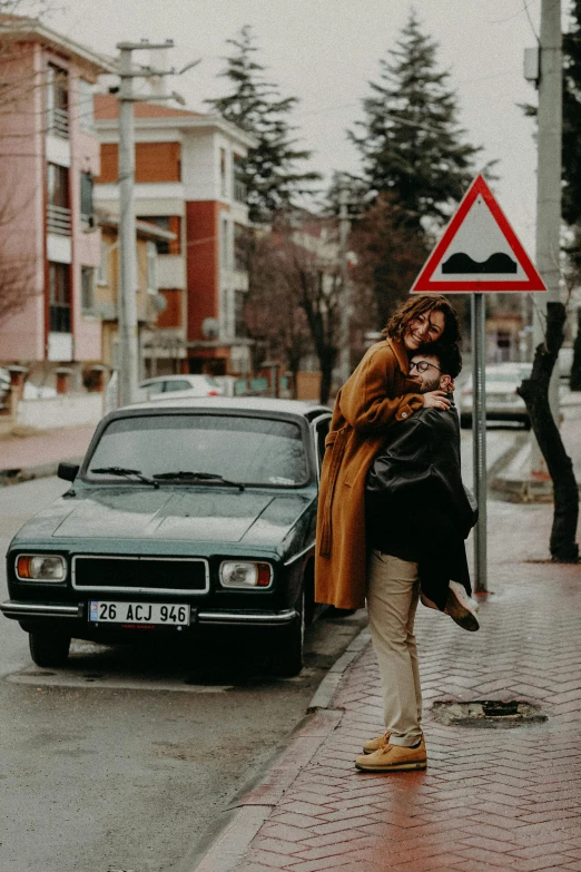 a woman standing on the side of a road next to a car, a picture, pexels contest winner, renaissance, lovely couple, street signs, 70s photo, hugging